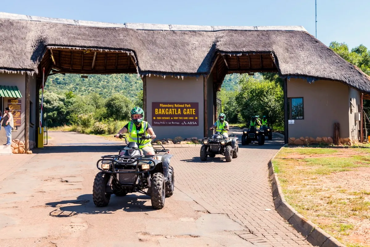 Quad bike riders in safety vests riding out of Bakgatla Gate, Pilanesberg National Park