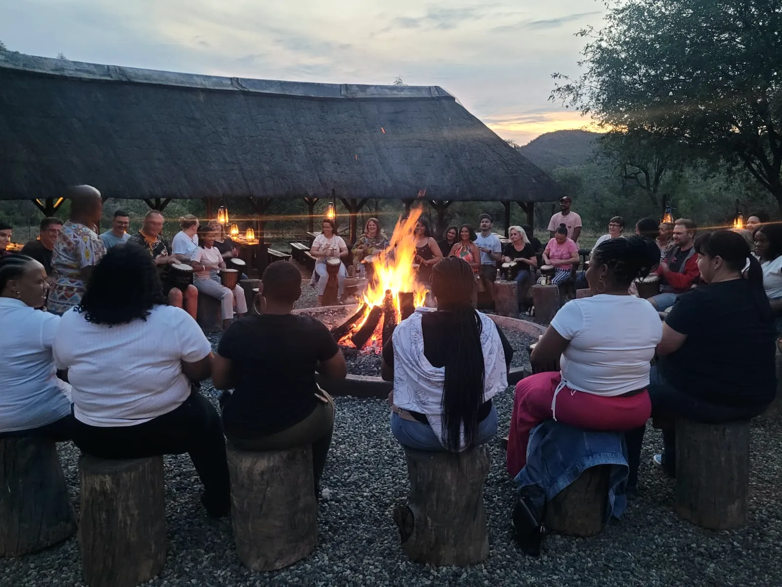 Guests drumming around a campfire at dusk