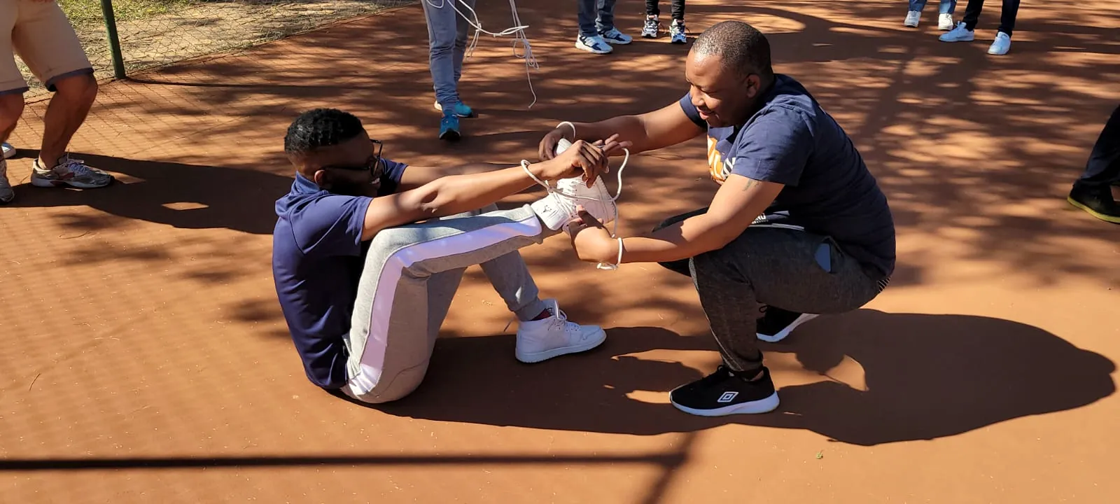 Two colleagues in a partner challenge on red sand