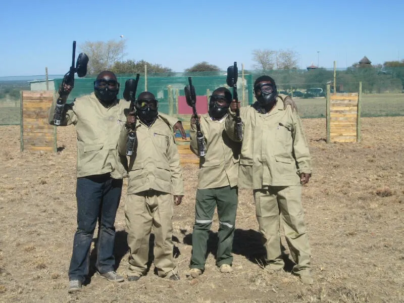 Four paintball players in masks and overalls